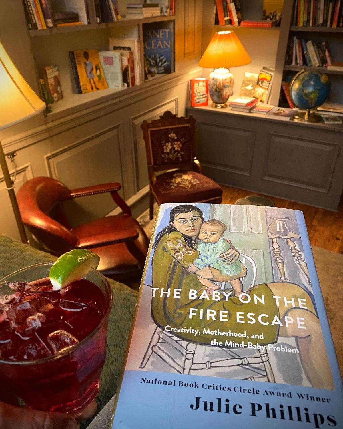 Space with bookshelves, a book and a cocktail on a table, closeup